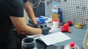 Mechanic in gloves fills form of car diagnostics at desk in workshop closeup. Worker hands marks points in documents for customer at service station - Powered by Shutterstock - Get 15% off with code: PIKWIZARD15