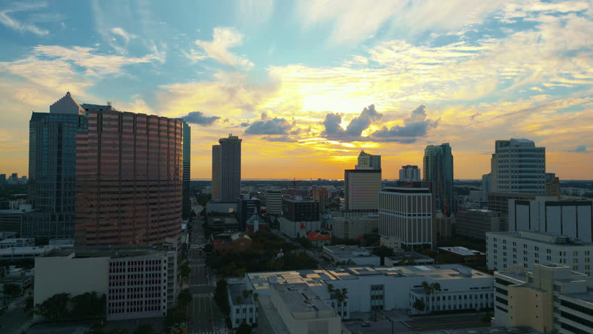 Tampa skyline at sunset as beautiful colors fill the sky and illuminate the clouds, aerial tracking left.