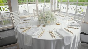 Elegant indoor wedding reception hall with white-decorated tables, floral centerpieces, and large windows overlooking lush greenery, creating a bright and romantic atmosphere. - Powered by Shutterstock - Get 15% off with code: PIKWIZARD15