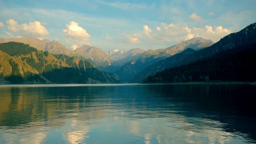 A serene and majestic mountain landscape with a calm lake reflecting the sky. A beautiful and peaceful nature scene perfect for travel and relaxation concepts.