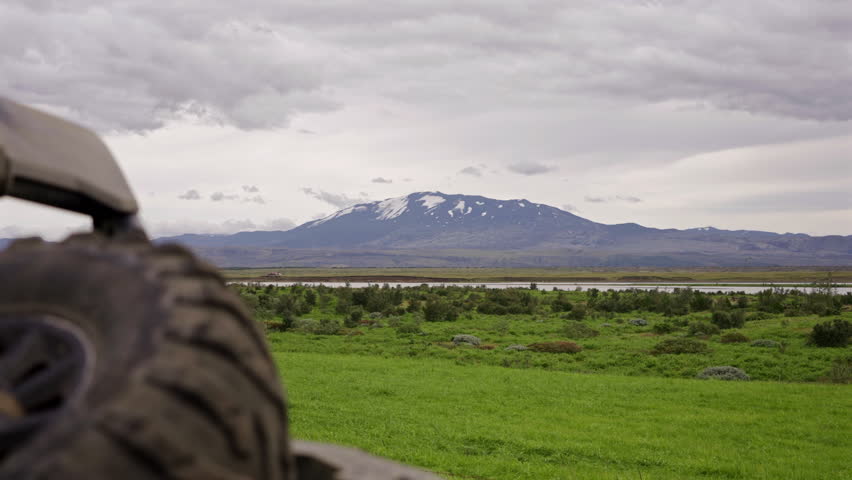 Offroad buggy parked in green valley with mountain backdrop