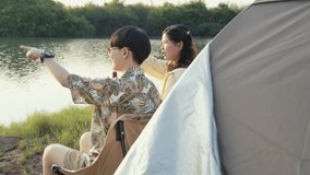 Asian couple or close friends relaxing by their camping tent, sitting on chairs, quietly enjoying bottled beer and the peaceful lakeside sunset view together - Powered by Shutterstock - Get 15% off with code: PIKWIZARD15