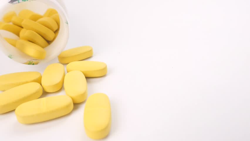 Close-up of Yellow Oval Pills Spilled from a Bottle 4k