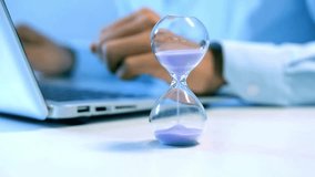 Timelapse of an hourglass with sand running out on an office desk. A busy businessman types on a laptop, symbolizing deadlines and time management. - Powered by Shutterstock - Get 15% off with code: PIKWIZARD15
