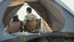 Romantic back view of an Asian couple sitting together inside a tent, silently watching the tranquil sunset over the lake during their camping date - Powered by Shutterstock - Get 15% off with code: PIKWIZARD15