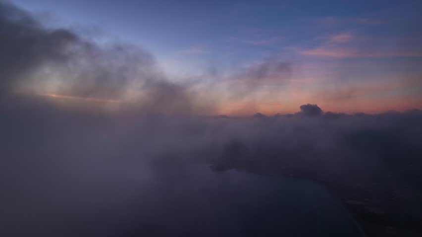 Aerial view of a coastline under heavy clouds, where the sea meets the land in a serene, shadowy embrace, Ibiza, Balearic Islands, Spain.