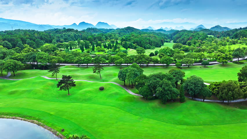 Aerial shot of the beautiful golf course and green forest with mountain natural landscape in summer