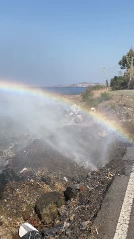 Vertical view of a colorful rainbow arching over landscape after shower