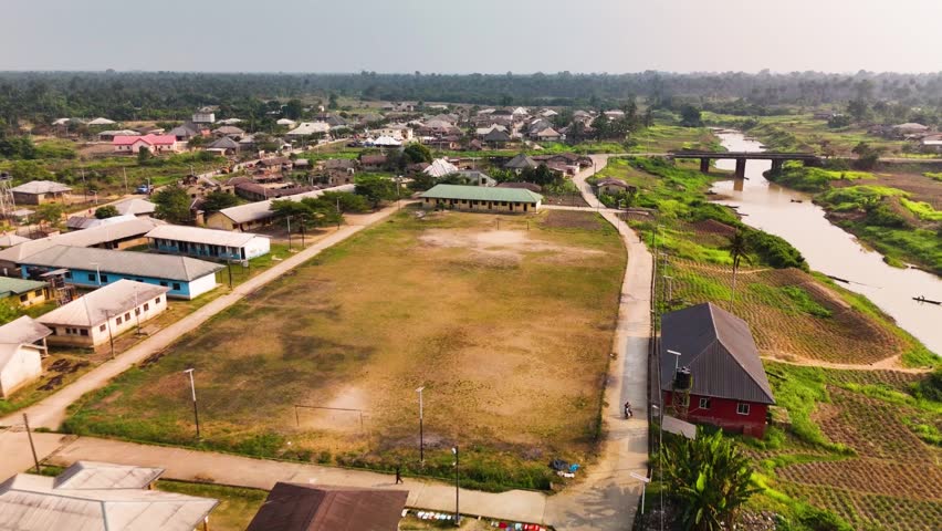 Aerial view of buildings with assorted rooftops, a bridge over the river, and lush green vegetation, Biseni, Bayelsa State, Nigeria.