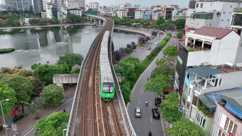 Cat Linh–Ha Dong metro train running along Hoang Cau lake, vibrant urban morning scene.