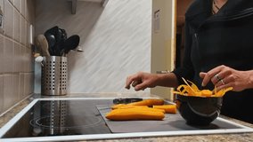 Close-up of a woman in her European home kitchen tasting a freshly peeled carrot, unable to wait for her meal to be done. A small bowl with peel and shiny carrots sits beside her - Powered by Shutterstock - Get 15% off with code: PIKWIZARD15