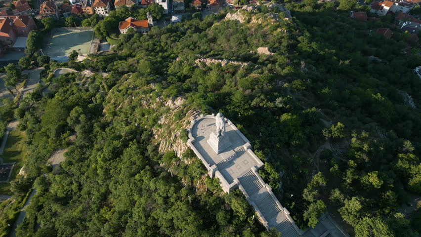 Drone footage of Bunardzhik Hill and the Alyosha Monument in Plovdiv at sunrise. View of the city, Youth Hill, and the Rhodope Mountains in springtime