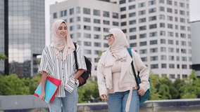 Two muslim female students in hijabs walking and talking together on campus - Powered by Shutterstock - Get 15% off with code: PIKWIZARD15