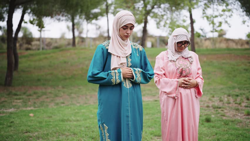 Muslim women in traditional dress praying outdoors