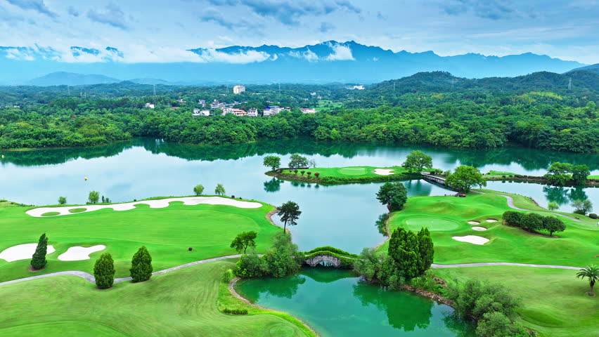 Aerial shot of the beautiful green golf course and calm lake with mountain natural landscape in summer