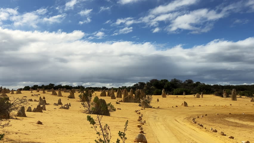 Scattered rock structures rise from golden sand in the Pinnacles Desert in Western Australia