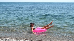 Woman beach splashing with pink inflatable ring on sunny summer day - Powered by Shutterstock - Get 15% off with code: PIKWIZARD15