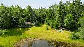  A serene drone shot captures a classic wilderness camp with canoes resting on a pristine shore, backed by the majestic Adirondack Mountains. - Powered by Shutterstock - Get 15% off with code: PIKWIZARD15