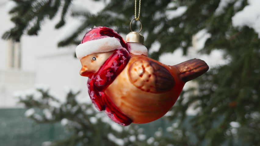 Christmas bird ornament hanging among snow frosted pine branches wearing scarf Santa hat symbolizing love joy handmade holiday decor artistic composition inspiring festive home design peaceful winter