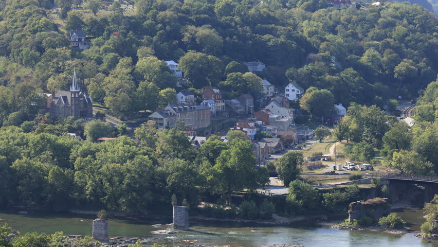 High angle view of historic Harpers Ferry where the Potomac and Shenandoah Rivers meet. The town’s old bridge ruins and church spires highlight its scenic and historic charm on a late summer day.