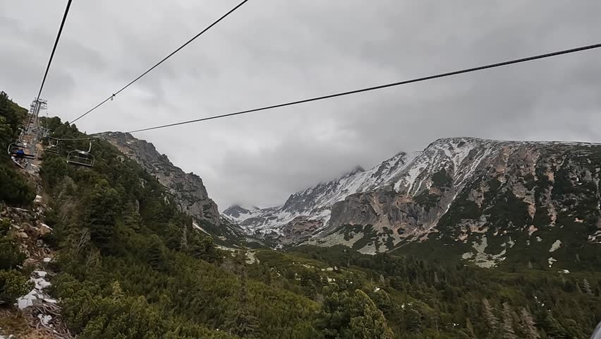 Open ski lift. Empty suspended chairlift seat against the backdrop of mountain slopes. Tatra Mountains, Slovakia.