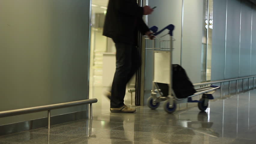 People with travel wheel bags coming out of airport arrival zone after flight