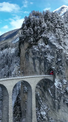 Aerial view of Train passing through famous mountain in Filisur, Switzerland. Landwasser Viaduct world heritage with train express in Swiss Alps snow winter scenery.