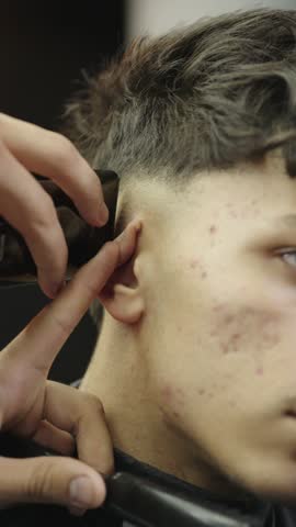 Barber giving a young man a haircut with a hair clipper