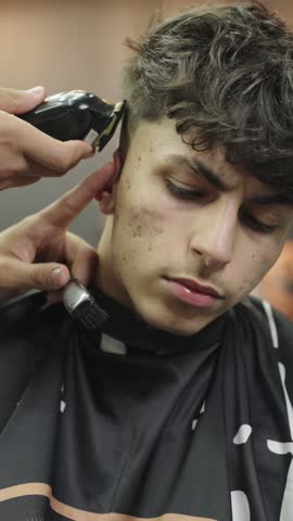 Professional barber cutting hair with electric trimmer