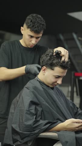 Professional barber giving haircut to customer in barbershop