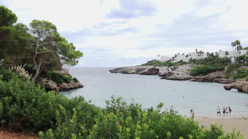 People enjoying the views of Cala Esmeralda beach in Cala d'Or village on Mallorca island in Spain.