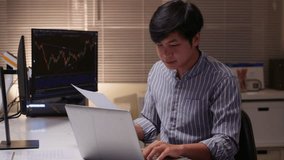 Young Asian trader analyzing financial charts on computer at night - Powered by Shutterstock - Get 15% off with code: PIKWIZARD15