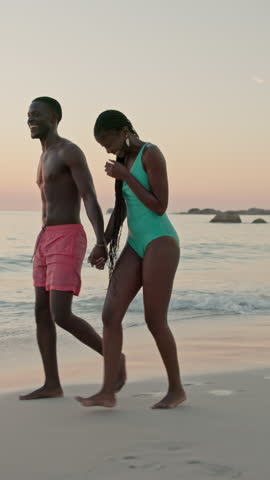 Beach, holding hands and black couple with vacation, sunset and bonding together with laughing. People, ocean and man with woman, smile and love with joke, honeymoon and relationship with holiday