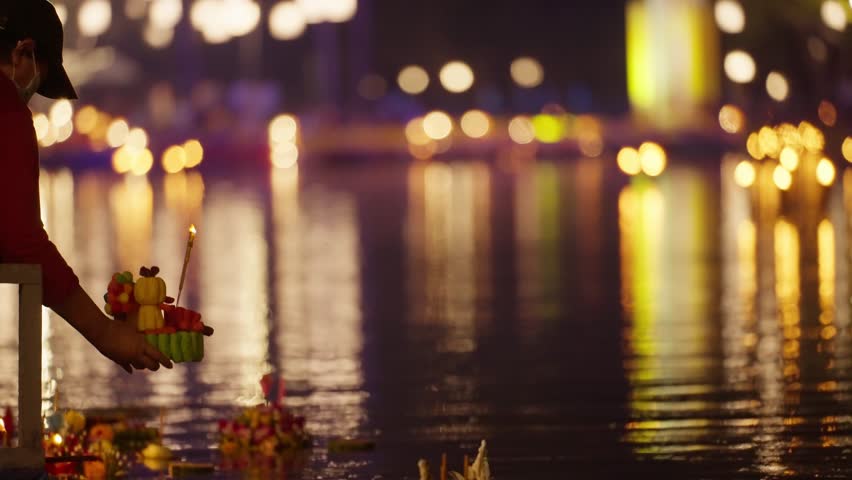 Loy Krathong festival with colorful candles light and full moon in Thailand, Floating ritual banana leaves vessel or lamp and lotus flower into the water traditional