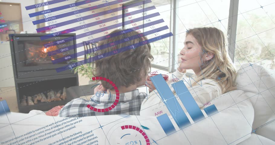 Couple raising mugs while sitting on sofa with finance charts drifting converging analyzing markets. Cozy, companionship, relaxation, technology, home, comfort, warmth