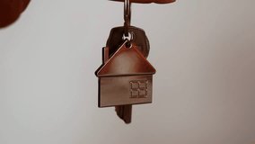 House key with a home-shaped keychain in a man’s hand, symbolizing property ownership. - Powered by Shutterstock - Get 15% off with code: PIKWIZARD15