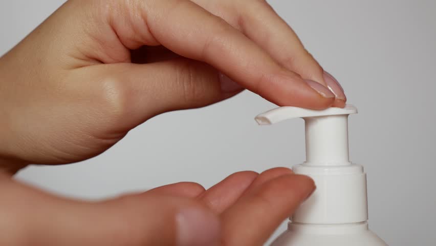 Detailed shot of hands using hand sanitizer.