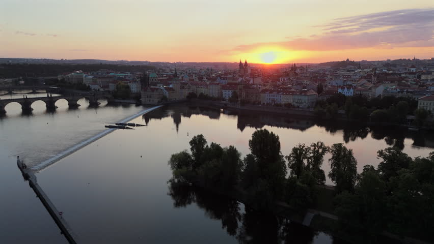 Immerse yourself in the breathtaking beauty of Prague skyline as the sun sets, casting a warm glow on the iconic Charles Bridge and creating tranquil reflections on the serene river. Czech Republic 