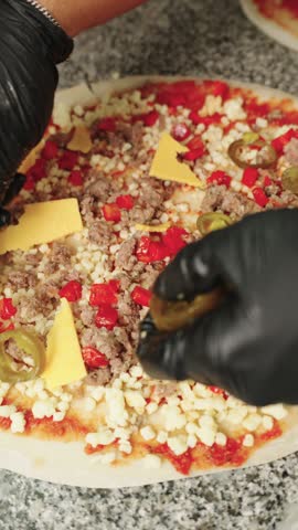 Chef in black gloves preparing a spicy mexican pizza