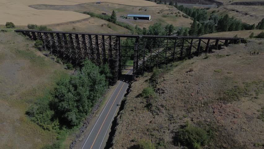 Abandoned railroad trestle in Idaho. Flight passes over the trestle and shows the trestle, canyon below, and surrounding plains with farmlands of the area.