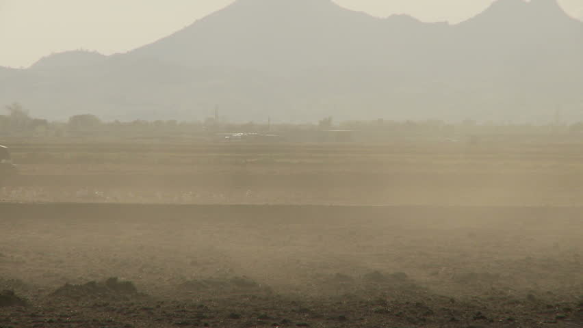 Tractor drives past screen in harsh lighting