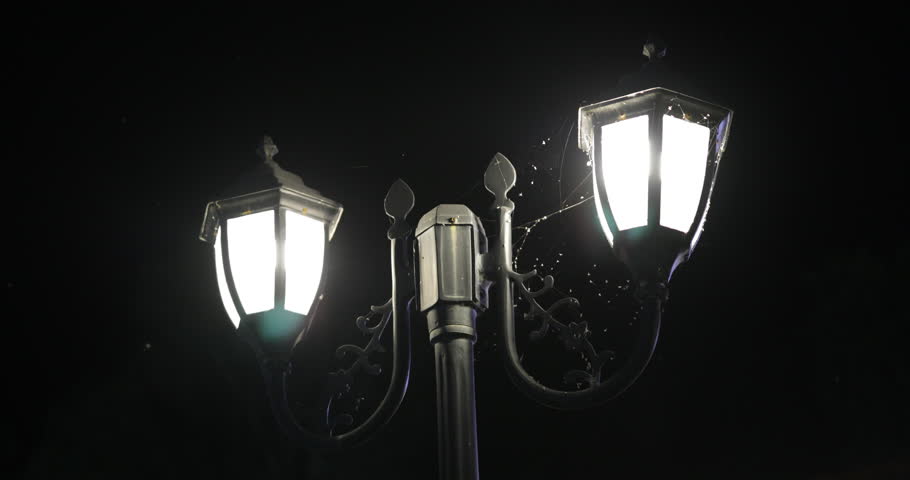 4K horror footage captured on Canon 5D Mark IV showing an old street lamp glowing dimly outside a bungalow at night. Light fog, mist, and spider webs create a mysterious and eerie cinematic atmosphere