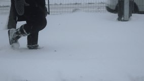 Woman slowly walks through deep snow in boots in city near fenced road, side view. Bad condition of sidewalks after snowfall and snowstorm. Difficult winter weather conditions after storm. - Powered by Shutterstock - Get 15% off with code: PIKWIZARD15