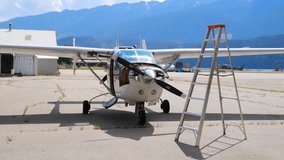 Teal overlay appearing over prop hub, plane performing scan near ladder, shifting and opening panel. Aviation, diagnostics, maintenance, technology, inspection, rugged, modern - Powered by Shutterstock - Get 15% off with code: PIKWIZARD15