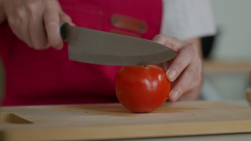 Hands cutting of fresh tomatoes in a kitchen as glowing nutrient icons-vitamin A, C, K, lycopene, and magnesium-highlight their health benefits.