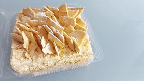 Flaky pastry shards crown a creamy Napoleon slice in a clear container-golden, textured, and indulgent. A close-up that highlights crisp layers and rich, tactile detail - Powered by Shutterstock - Get 15% off with code: PIKWIZARD15