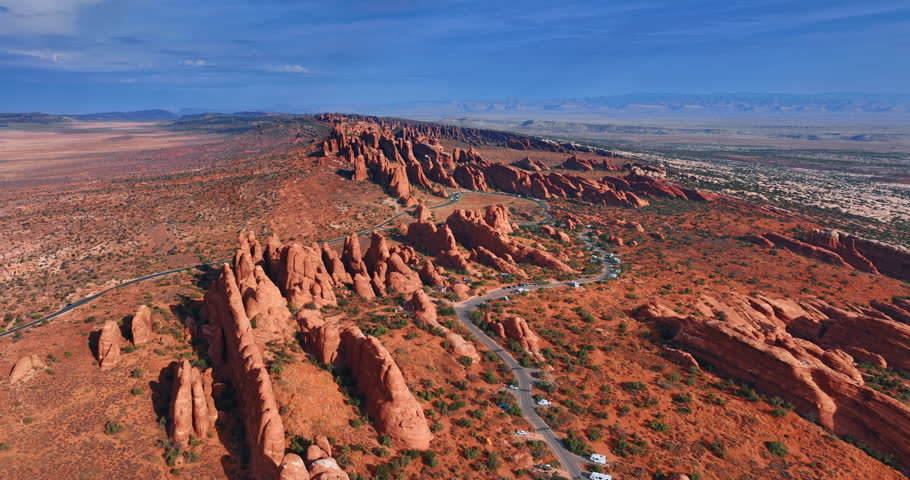 Ridged rocks with rounded tops outlined by the highway. Scenic view on the the Arches National Park, Utah, USA from drone.