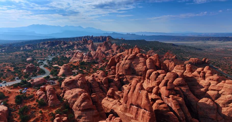 Iconic view on the amazing canyons in the Arches National Park, Utah, USA. Campervans with tourists stand parked at the highway. Aerial view.