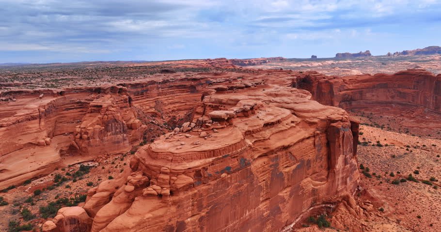 Approaching a red canyon with steep walls and flat top. Amazing rocks in the Arches National Park, Utah, USA from drone footage.