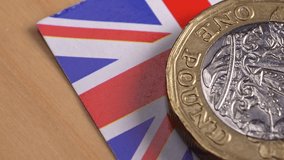 Macro view of a one pound coin alongside the Union Jack flag, representing the United Kingdom's economic crisis, rising inflation, cost of living issues, and post Brexit financial challenges - Powered by Shutterstock - Get 15% off with code: PIKWIZARD15
